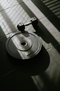 Dumbbell and weight plate on gym floor representing strength training and fitness performance